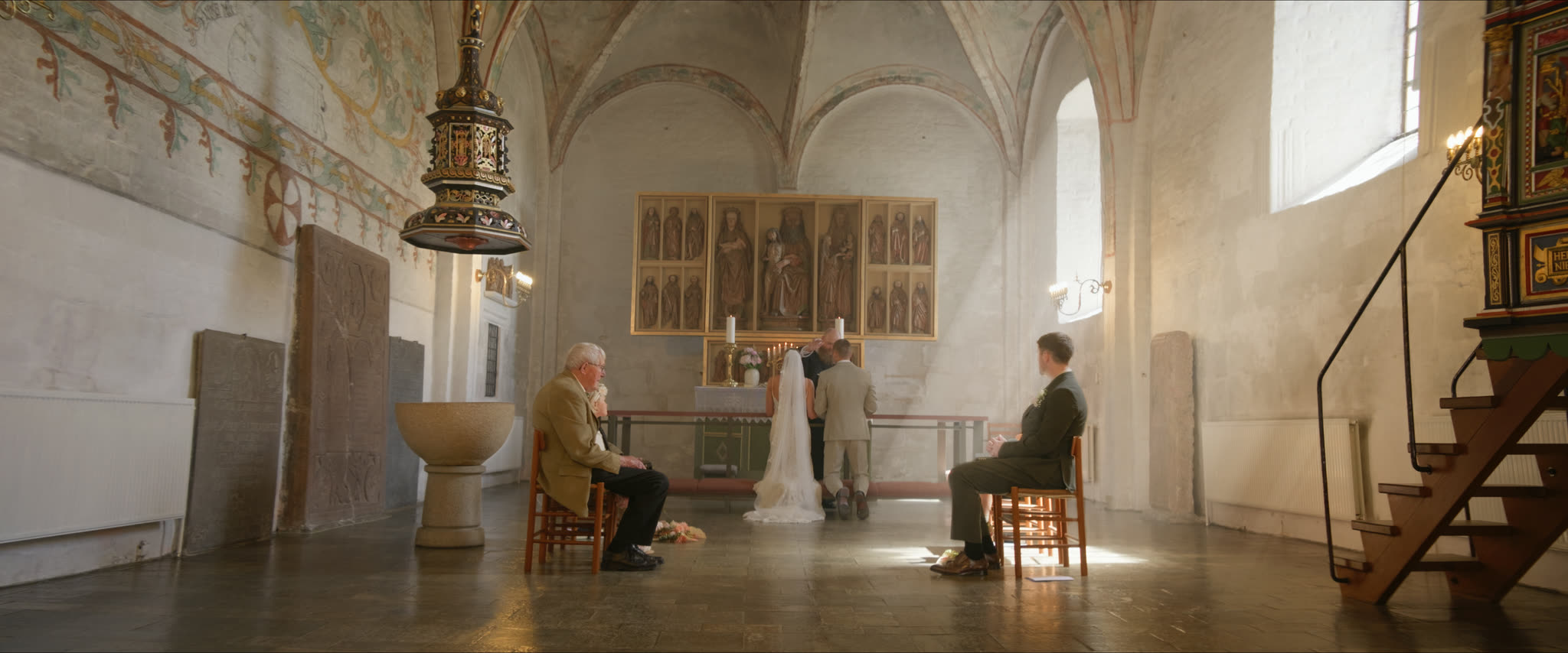 Vielse i en hvidkalket kirke med altertavle og gæster